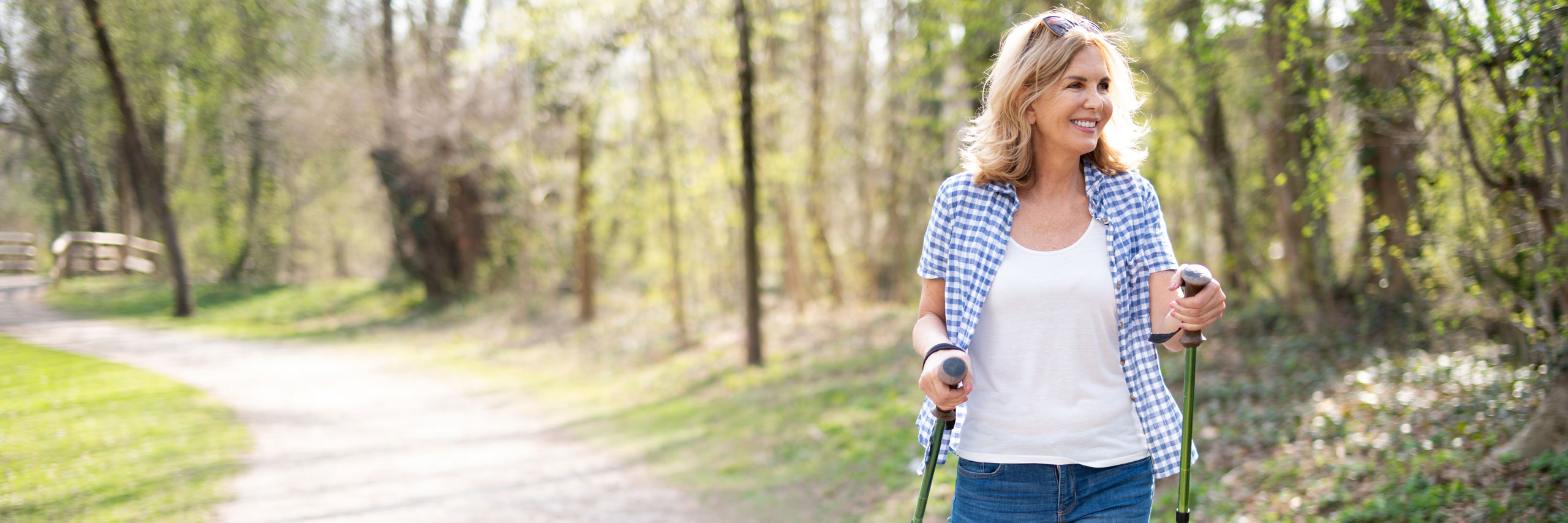 AdobeStock_259617414_2560x854px Frau beim Nordic Walking im Park