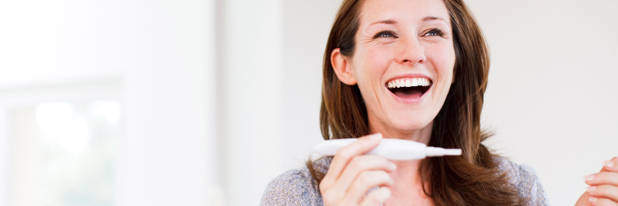iStock-107429839_2560x854px Frau freut sich über Ergebnis Schwangerschaftstest